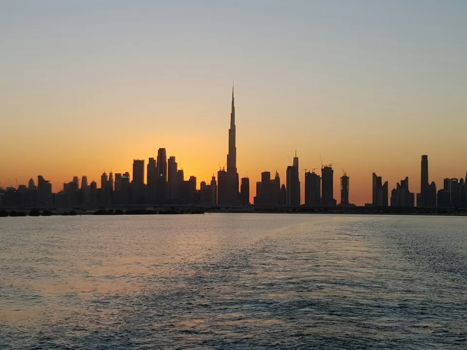 Dubai skyline with Burj Khalifa silhouetted at sunset across the water