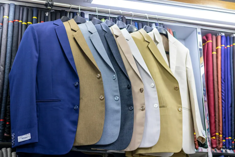 Rail of suit jackets in assorted colours with fabric bolts behind